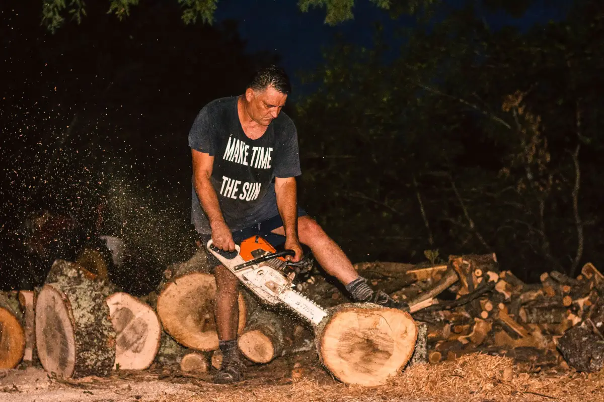 Worker using a chainsaw to section a downed tree