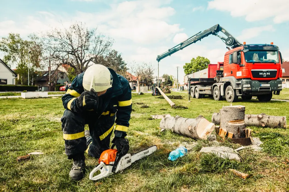 Arborist in safety gear working beside a crane truck